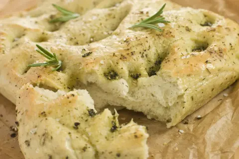 Frisch gebackene italienische Focaccia mit Rosmarin und grobem Salz, auf Backpapier.