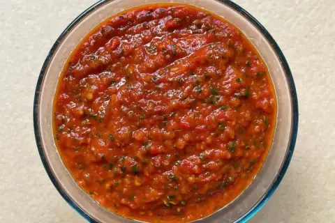 Bagnetto rosso piemontese in una ciotola di vetro, un condimento saporito e piccante, perfetto per accompagnare bolliti e carni.