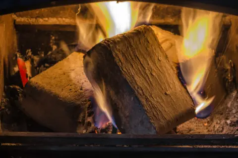 Zwei Holzbriketts brennen im Kamin. Die lange Brenndauer sorgt für wohlige Wärme.