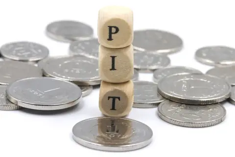 Drewniane klocki z literami "PIT" na stosie monet. Działalność nierejestrowana jaki PIT?