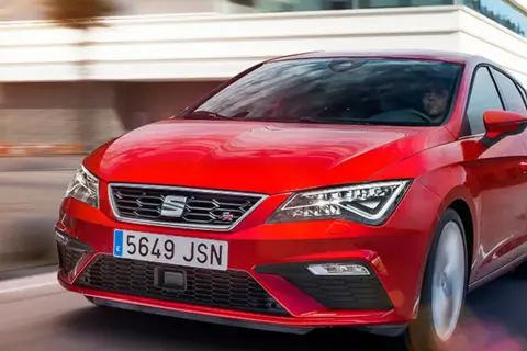 Czerwony Seat Leon 2025 pędzi po drodze, jego sportowy design przyciąga wzrok.