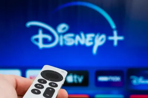 Pilot w dłoni, ekran z logo Disney+. Dowiedz się, jak dodać aplikacje do telewizora LG, by cieszyć się ulubionymi treściami.