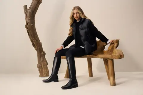 Eleganckie kozaki z szeroką cholewką idealnie uzupełniają stylizację z puchową kurtką i czarnymi legginsami.