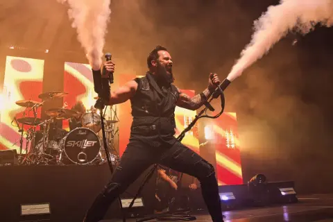 Skillet na koncercie w Warszawie, wokalista John Cooper strzela dymem z ręki.
