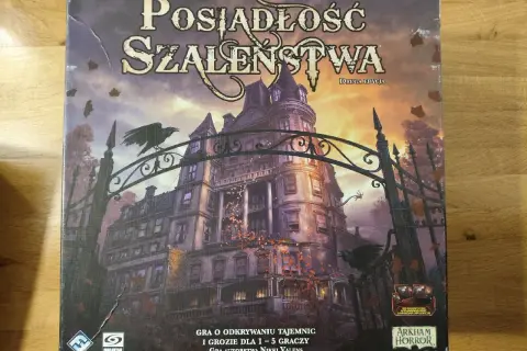 Okładka gry planszowej "Posiadłość Szaleństwa" z mroczną posiadłością i wronami. Scenariusze tej gry przeniosą Cię w świat tajemnic i grozy.