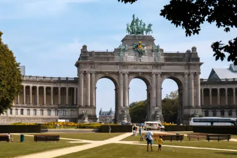 Łuk Triumfalny w Parku Cinquantenaire, Bruksela. W tle widać budynki muzealne i autokar, symbolizujący komunikację miejską Brukseli.