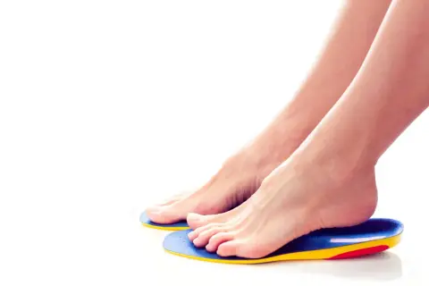Piedi femminili appoggiati su ortesi per piede colorate, per un comfort e supporto ottimali.