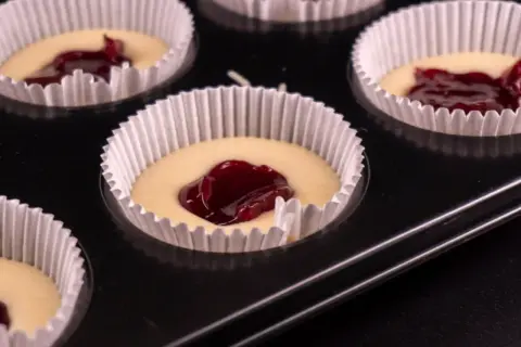 Nadziewane dżemem muffinki w papierowych foremkach w blaszce.