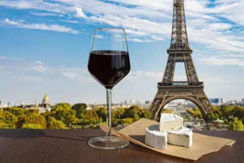Ett glas rött vin och ost framför Eiffeltornet, som används för att visa upp Paris kultur och skönhet.
