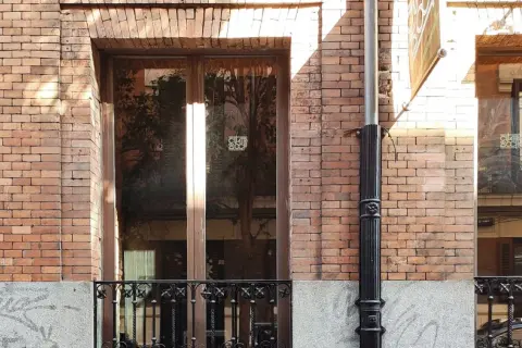 Fachada de ladrillo con ventanas y puerta de madera. El mantenimiento de fachadas es clave para conservar su belleza y estructura.