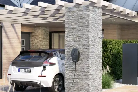 Ein weißes Elektroauto lädt an einer Ladesäule. Im Hintergrund ein modernes Haus mit Wärmepumpe und Solaranlage. Perfekt für die evu sperrzeit.