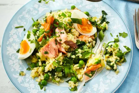 Reisgericht mit Lachs, Erbsen und Ei – ein Beispiel für gesund und lecker kochen. Frische Kräuter verfeinern die Mahlzeit.