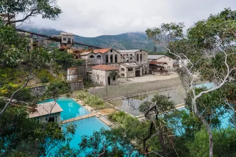 Antica zona mineraria sarda con edifici abbandonati e vasche d'acqua turchese.