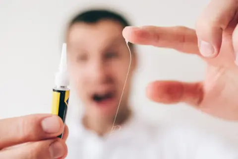 Zastanawiasz się, czym zmyć super glue z rąk? Oto mała nić, która przykleiła się do palca, obok tubki kleju.