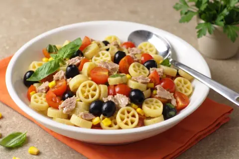Un piatto invitante di pasta fredda saporita con tonno, pomodorini, olive nere e mais. Fresca e colorata, perfetta per l'estate.