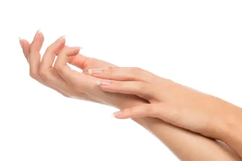 Dwie zadbane dłonie z paznokciami w stylu francuskiego manicure na białym tle.