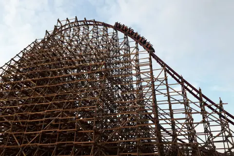 Drewniana konstrukcja rollercoastera w Energylandii, z wagonikami wjeżdżającymi na szczyt. Czy Energylandia jest otwarta w deszcz?