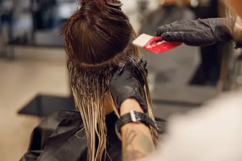 Friseur trägt Farbe auf, um einen sanften Farbverlauf zu erzielen. Die color melting Technik lässt die Töne harmonisch ineinander übergehen.