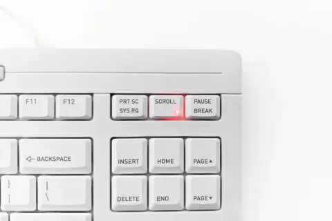Biała klawiatura z podświetloną na czerwono diodą przy klawiszu SCROLL LOCK. Klawisz PAUSE/BREAK obok.