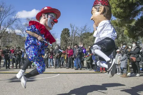 Gigantes y cabezudos saltan en una fiesta popular. Un payaso y un hombre con boina roja celebran el 5 de marzo.