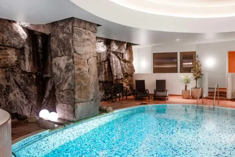 Avslappnande poolområde med stenformationer och bubbelpool, perfekt för en paus efter en dag som viking på ett hotell i Stockholm.