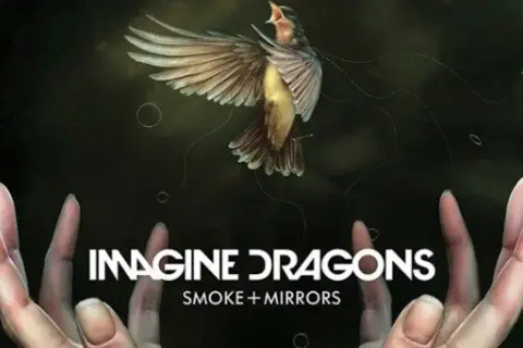 Ptak w locie nad dłońmi, z napisem "IMAGINE DRAGONS SMOKE + MIRRORS".