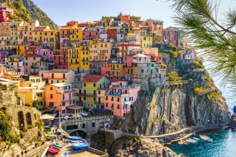 Färgstarka hus klättrar uppför klipporna vid havet i Italien. En vacker vy som ger fakta om Italien.