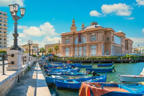 Barche blu ormeggiate nel porto, con il Teatro Margherita sullo sfondo. Un'immagine che cattura l'essenza di Bari e dintorni cosa vedere.