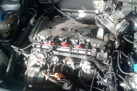Silnik Audi A4 B6 2.0 benzyna w trakcie prac. Widoczne cewki zapłonowe, przepustnica i alternator.