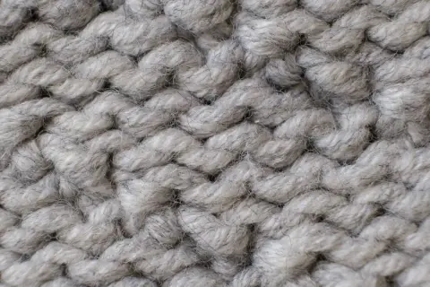 Nahaufnahme einer dicken, grauen Stricktextur. Die einzelnen Fäden sind flauschig und weich, ideal für das Mohair waschen.
