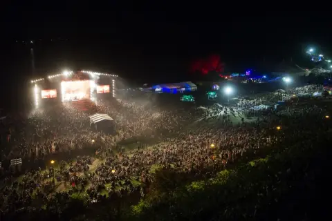 Tłum ludzi na koncercie festiwalu Audioriver, światła sceny i ekranów tworzą magiczną atmosferę nocnego wydarzenia.