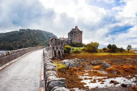 Kamienny most prowadzi do zamku Eilean Donan. Mglisty, jesienny klimat Szkocji podkreśla surowe piękno krajobrazu.