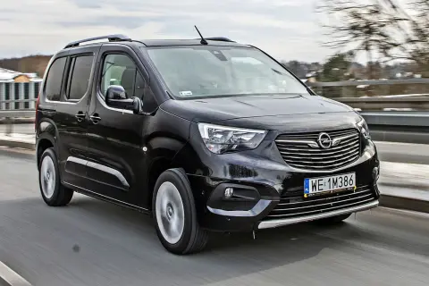 Czarny Opel Combo Life pędzi po drodze, gotowy na rodzinne przygody.