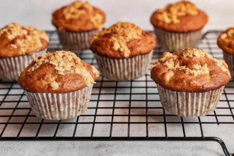 Mehrere goldbraune Haferflocken Muffins mit knuspriger Streusel-Decke auf einem Kuchengitter.