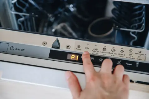 Palec naciska przycisk "Reset" na panelu zmywarki Beko, co może być pierwszym krokiem, jak zresetować zmywarkę beko.
