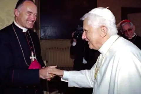 Papst Benedikt XVI. schüttelt einem Bischof die Hand. Im Hintergrund ein Kameramann und ein weiterer Geistlicher, ein Zeichen der Würde der summorum pontificum.