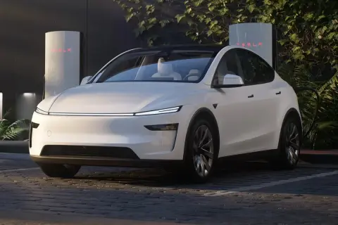 Biała Tesla zaparkowana przy ładowarce Supercharger.