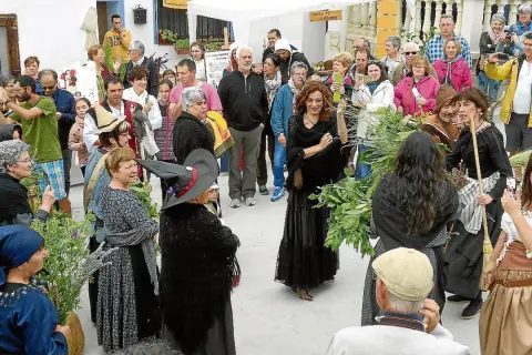 Gente celebra la fiesta de las brujas en Trasmoz. Mujeres vestidas de negro y con sombreros de bruja, rodeadas de hierbas y flores.
