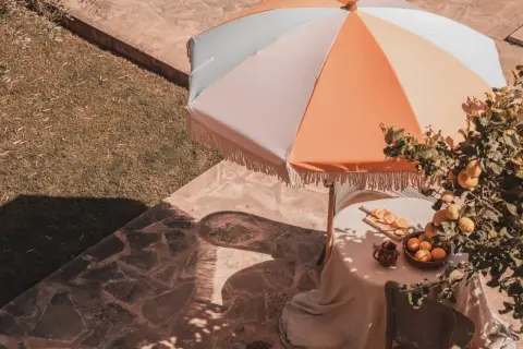 Kolorowy parasol ogrodowy nad stołem z cytrynami i pomarańczami.