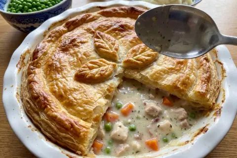 En gyllene kycklingpaj med krämig fyllning av kyckling, morötter och ärtor. Perfekt för ett mysigt kycklingpaj recept.