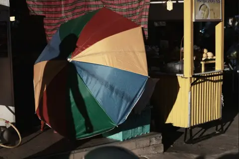 Kolorowy parasol rzuca cień na uliczny stragan z mango sticky rice. Tętniący życiem krajobraz miejski.