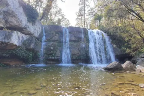 Cascada en la ruta 7 gorgs, con rocas cubiertas de musgo y vegetación, y un río de aguas claras.