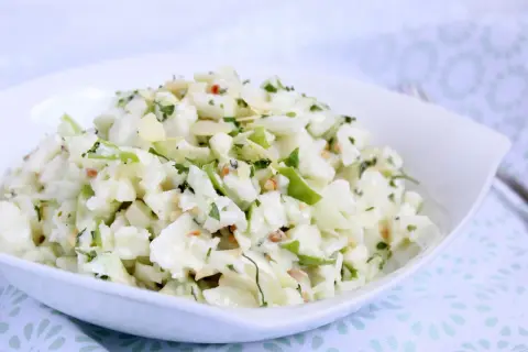 Ein **schneller Kohlrabisalat** mit Apfelstücken, Mandelsplittern und Petersilie in einer weißen Schüssel.