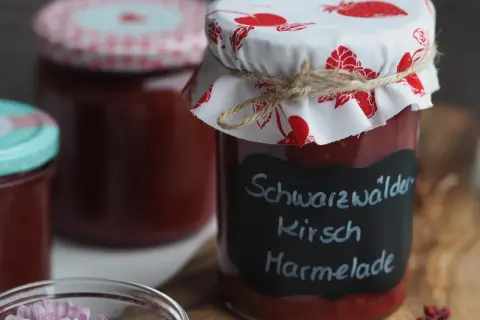 Glas mit hausgemachter Kirschmarmelade, beschriftet mit "Schwarzwälder Kirsch Marmelade". Ein tolles Rezept für den Sommer!