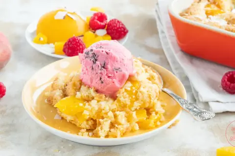 Ein warmer Pfirsich-Cobbler mit einer Kugel Himbeereis und frischen Himbeeren.