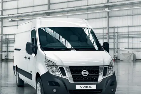 Biały van Nissan NV400 stoi w przestronnym magazynie.