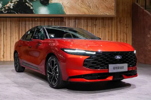 Nowy, lśniący, czerwony Ford Mondeo MK6 prezentuje się na tle drewnianej ściany i obrazu z krajobrazem.