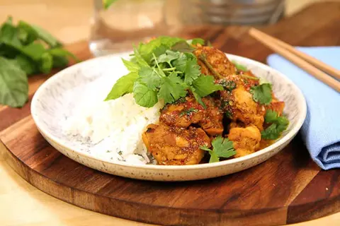 Kycklingrätt med ris, toppad med färska örter och en hint av citrongräs. En smakrik asiatisk måltid.