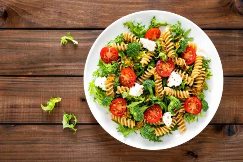 Kolorowa sałatka z makaronem fusilli, pomidorkami koktajlowymi, brokułami i fetą, polana musztardowym dressingiem. Pyszne danie na lekki obiad.