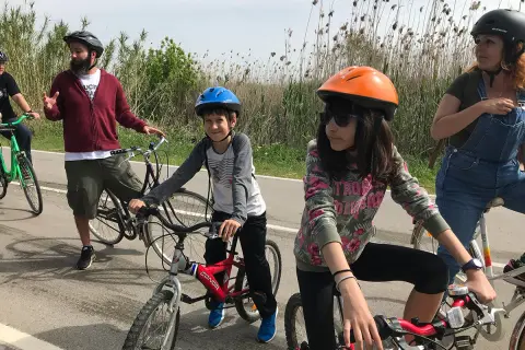 Familia disfrutando de rutas en bici con niños en Cataluña. Niños y adultos con cascos, listos para pedalear en un día soleado.